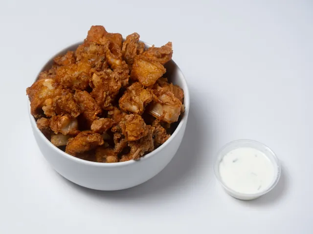 A bowl of fried calamari with a cup of tzatziki