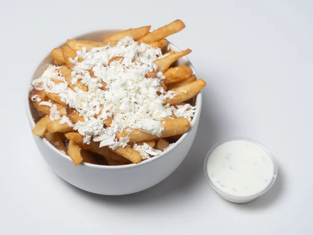 Fries topped with crumbled feta, with a cup of tzatziki