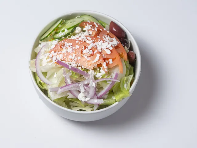 A bowl of Greek salad with tomato, red onion, cucumber, feta and olives