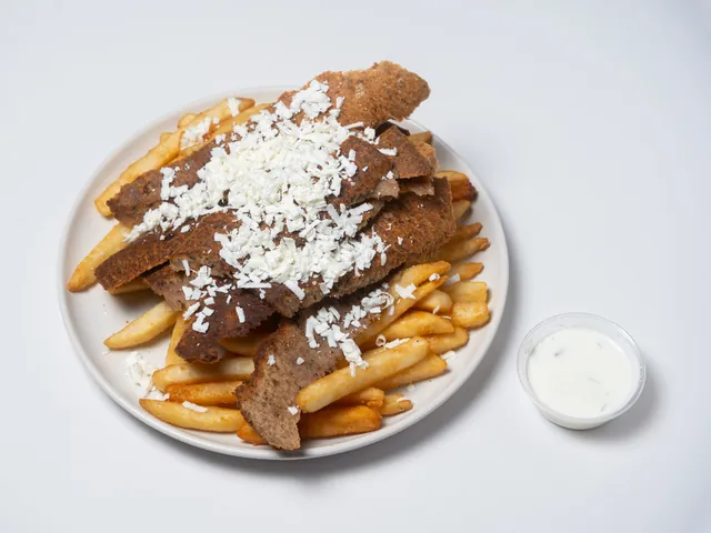 Fries topped with sliced gyro and crumbled feta, with a cup of tzatziki