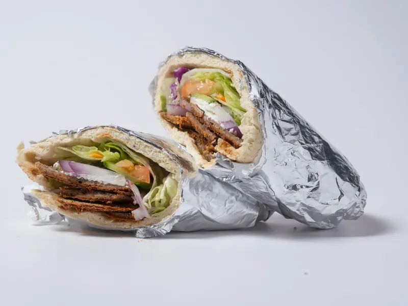 Two gyro classic pitas wrapped in foil, filled with lettuce, tomato, onion and feta