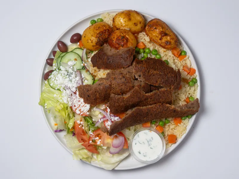 Gyro plate with rice, roasted potatoes, Greek salad and a cup of tzatziki