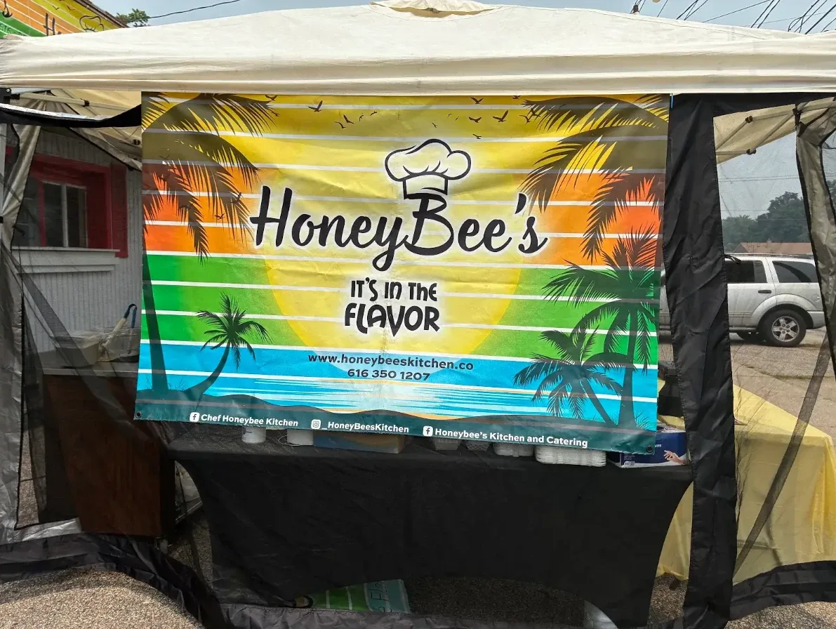 HoneyBee's Kitchen banner reading It's In The Flavor at an outdoor event tent in West Michigan