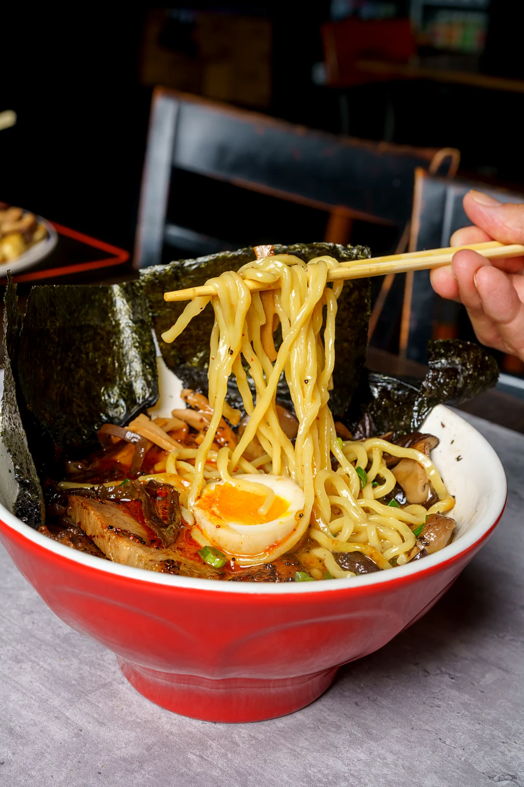 Noodles lifted from a bowl of Ichi-Kaku Ramen ramen with chashu, egg and nori
