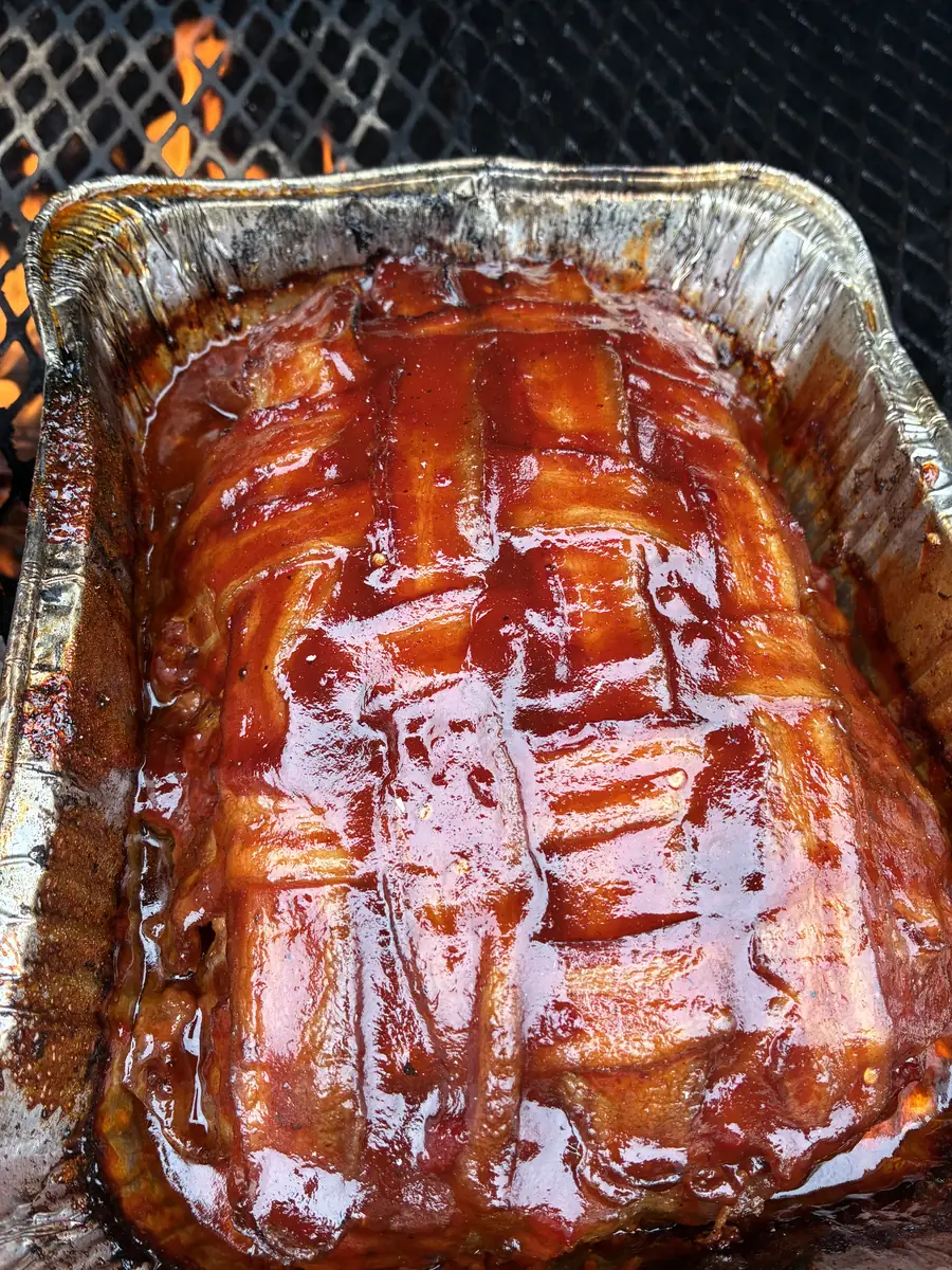 Bacon-wrapped turkey meatloaf glazed with barbecue sauce, finishing on the charcoal grill