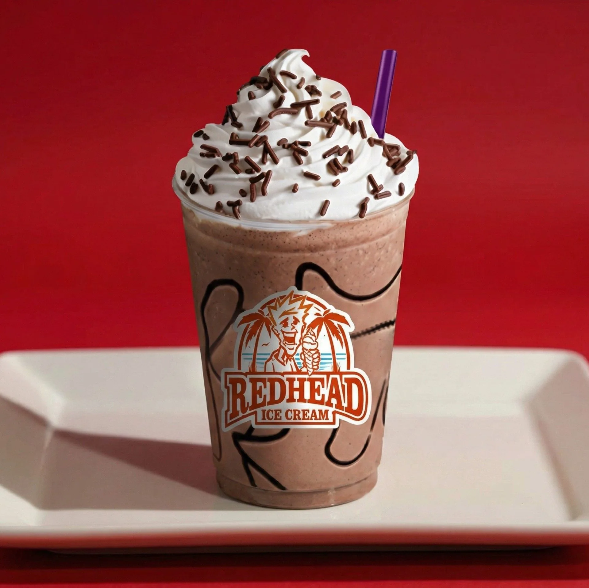 Redhead Ice Cream chocolate milkshake with whipped cream, chocolate sprinkles, and a purple straw.