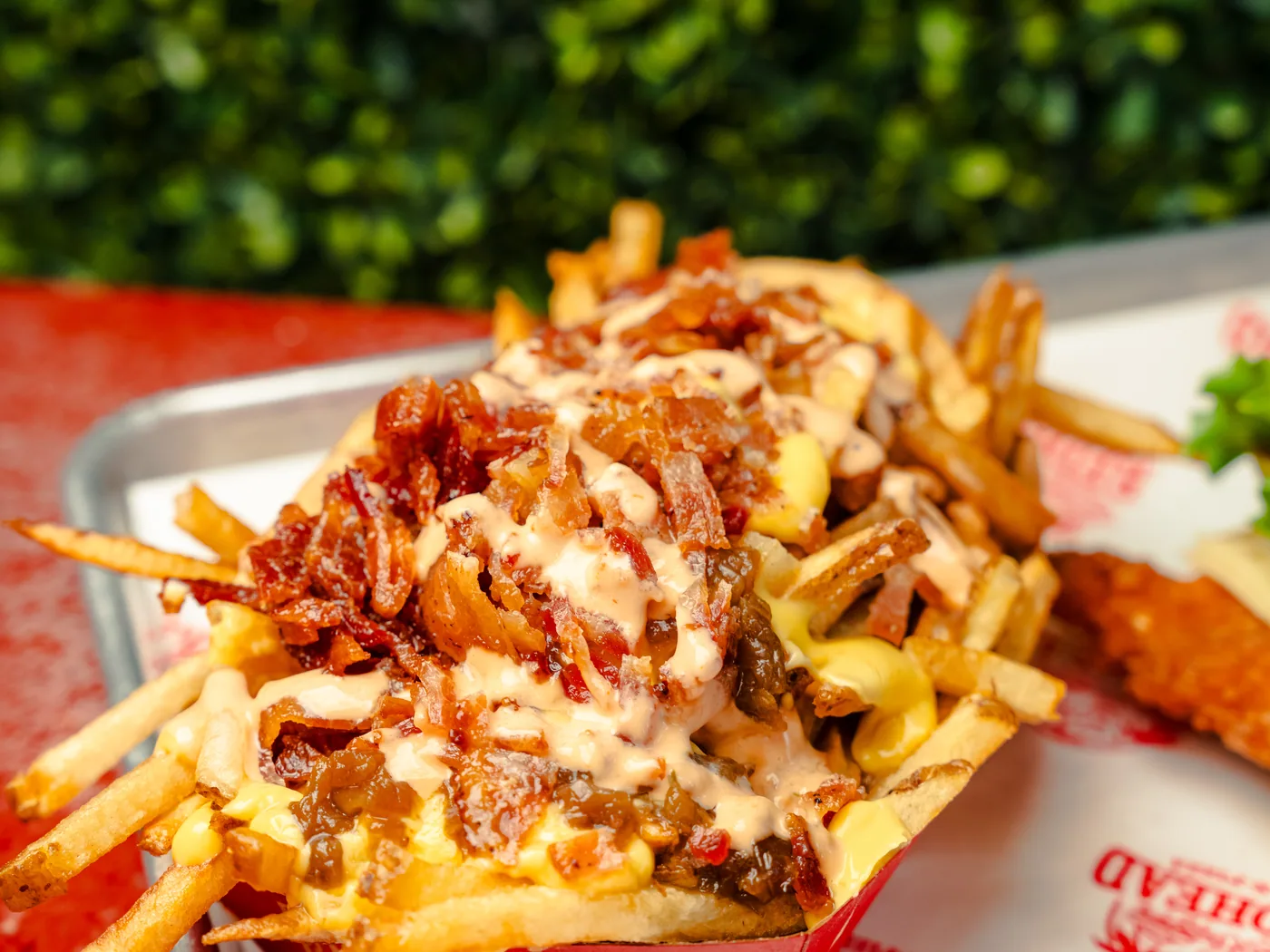Loaded fries piled with bacon and melted cheese on a Redhead Burger tray