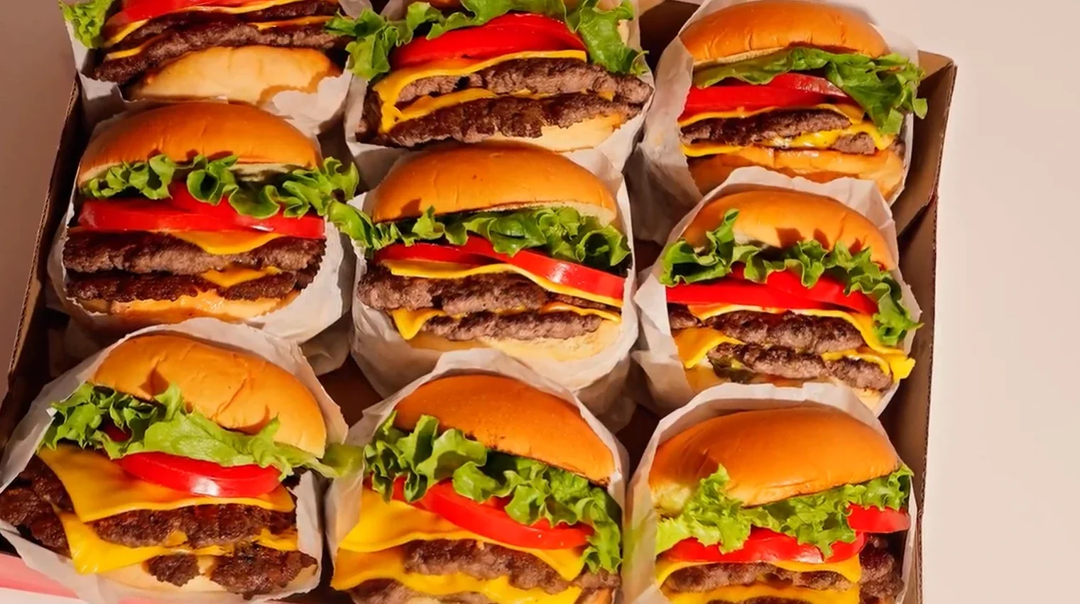 A catering box packed with nine Redhead Burger double cheeseburgers, ready for delivery.