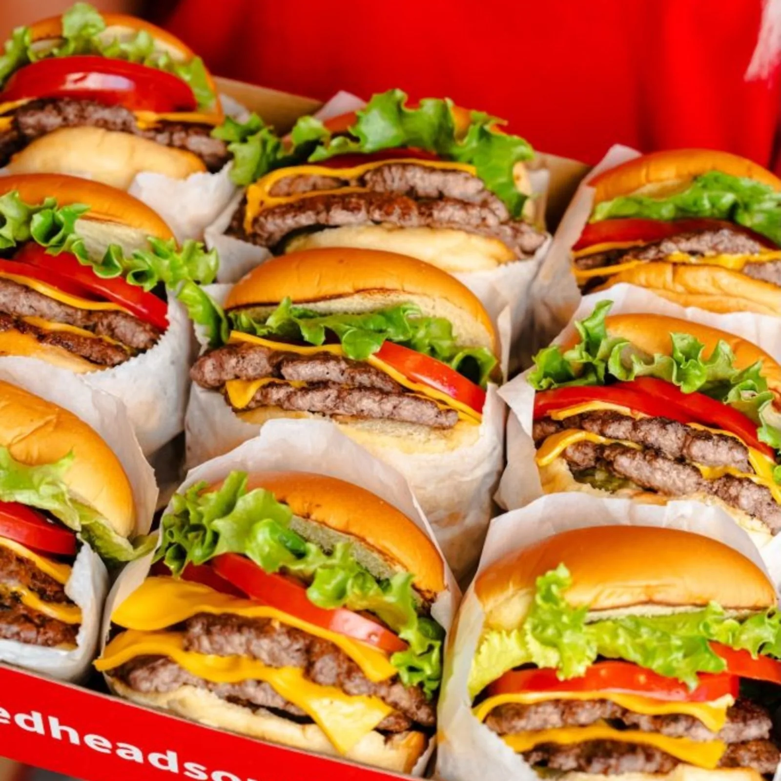 A dozen RedHead Burger double cheeseburgers with lettuce and tomato, individually wrapped in a red box.