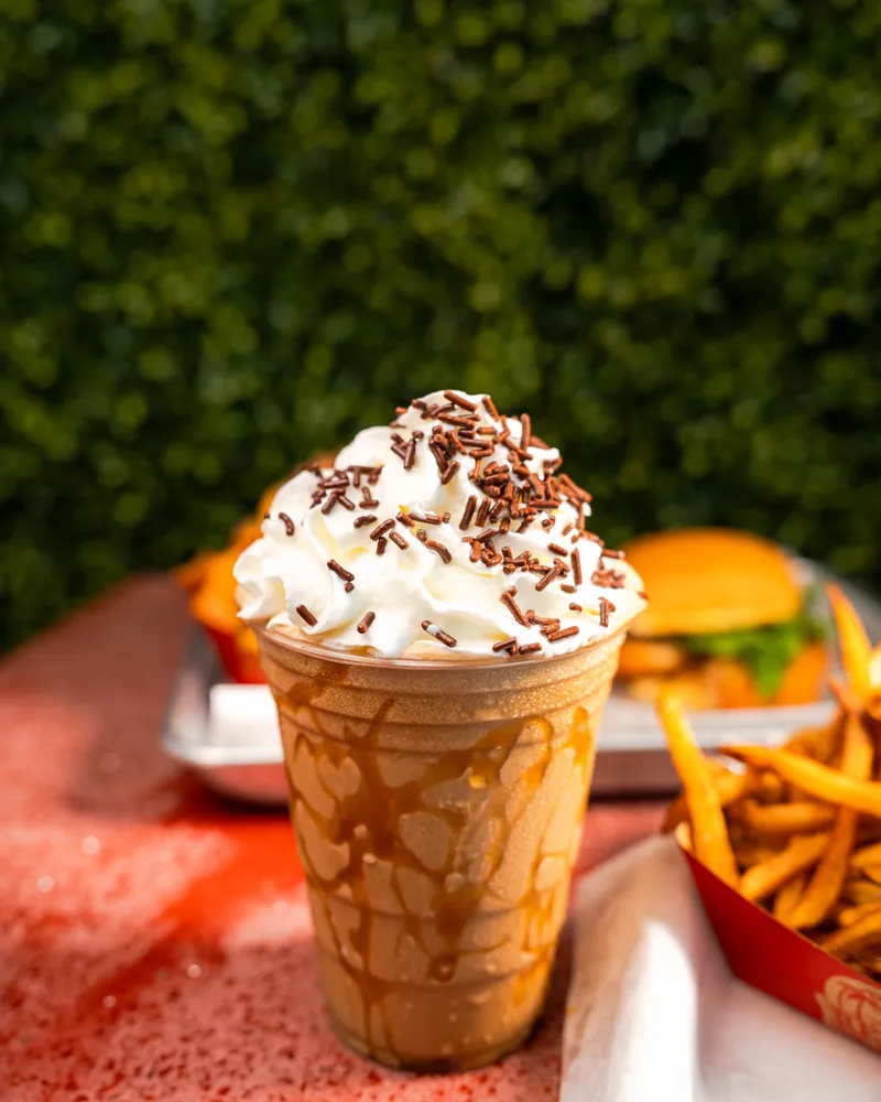 A thick Redhead milkshake with whipped cream next to a burger and fries