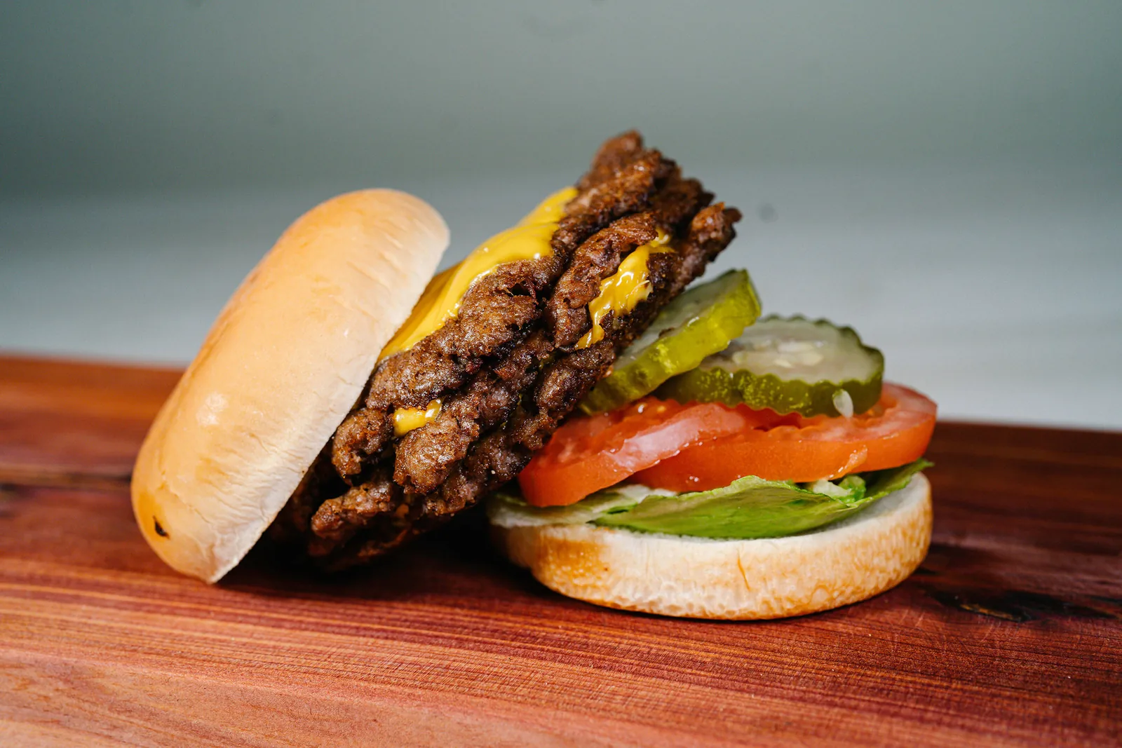 A smash burger with crispy edges, melted cheese, pickles, tomato and lettuce