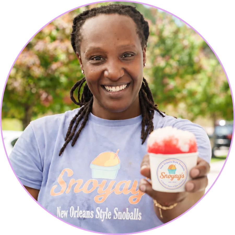 Jada Frazier, owner of Snoyay&rsquo;s, smiling and holding a snoball, wearing a Snoyay&rsquo;s New Orleans Style Snoballs t-shirt