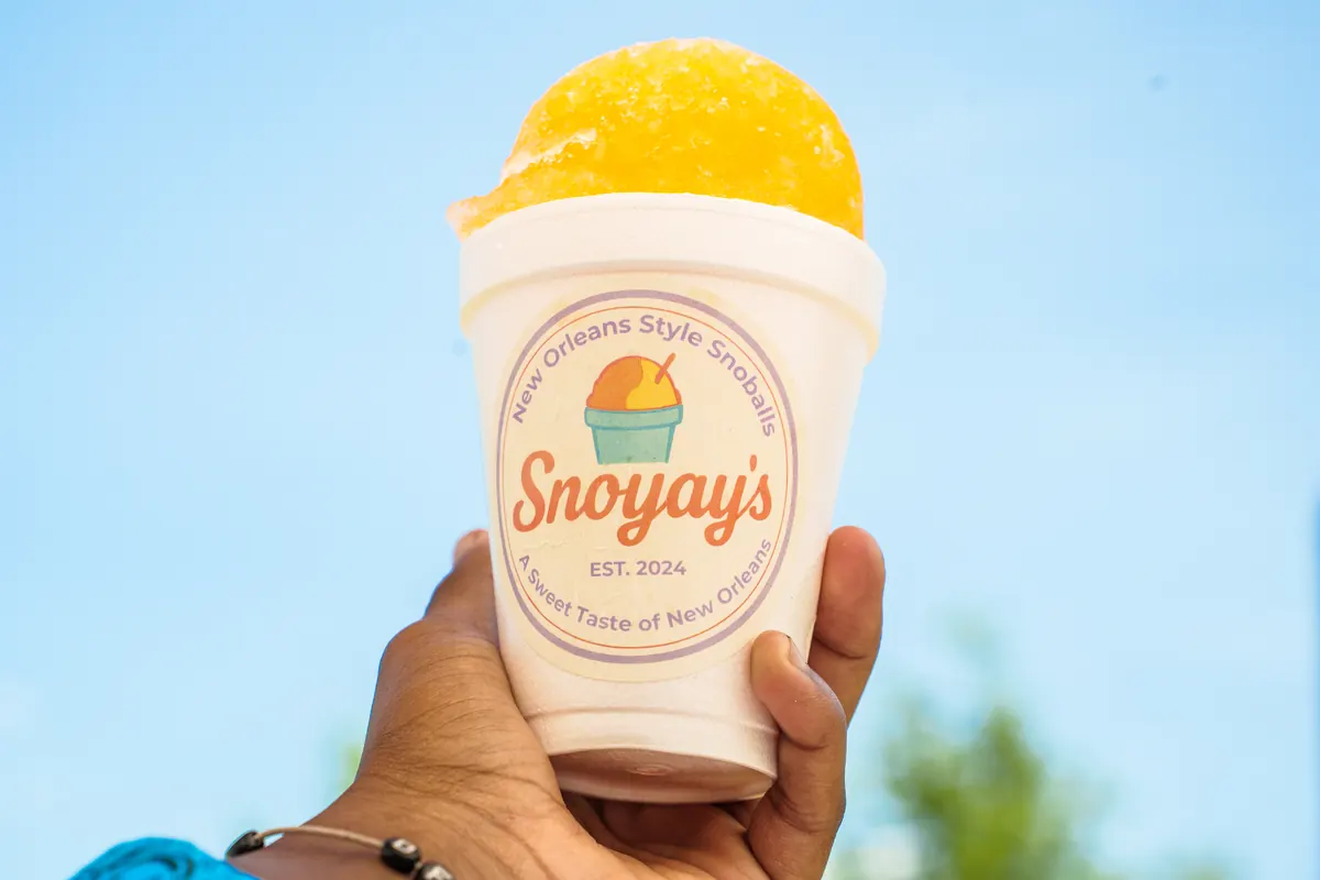 A yellow and orange snoball held up against a blue sky