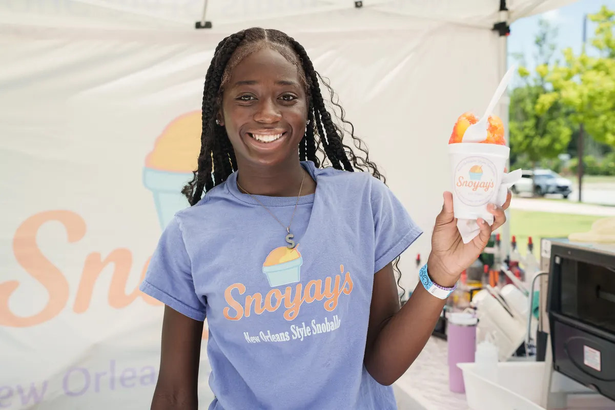 A Snoyay&rsquo;s team member in a lavender Snoyay&rsquo;s t-shirt holding a snoball